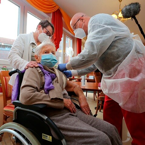 Doctor Bernhard Ellendt, right, injects the COVID-19 vaccine to nursing home resident Edith Kwoizalla, 101 years old, in Halberstadt, Germany.