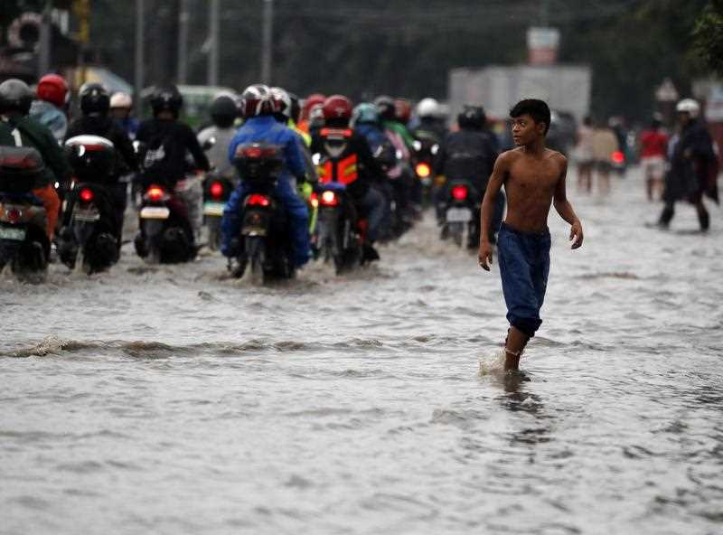 A Filipino navigates through flooded streets in Las Pinas city, south of Manila, Philippines, 18 July 2018.