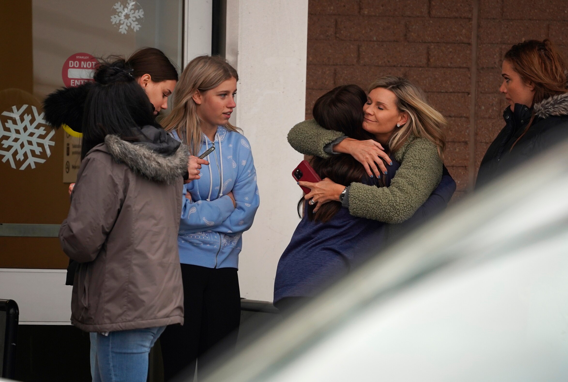 A parent hugs a child as other come to pick up students following an active shooter situation at Oxford High Schoolon November 30
