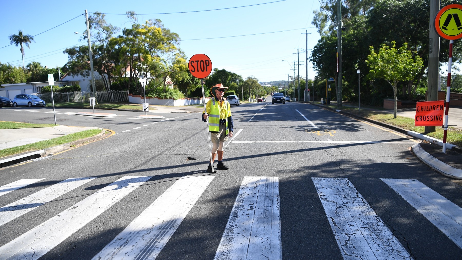 Pedestrian crossing attendant Peter (first name only given) performs his duty outside a primary school, in Brisbane, Monday, March 30, 2020.