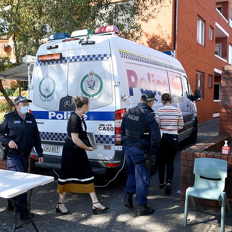 Health workers and Police officers are seen at a unit block under lockdown, in Campsie, south west of Sydney, Friday, August 20, 2021. (AAP Image/Dan Himbrechts) NO ARCHIVING
