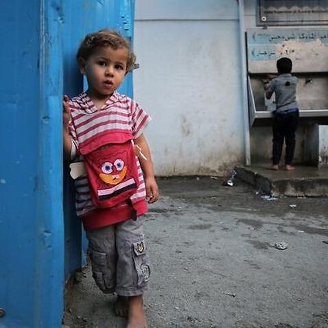 : Palestinian refugee boys fill containers with drinking water