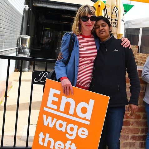 Former employees Shojin Thomas (centre) and Ninumol Abraham are seen near the Indian Restaurant Binny's Kathitto in Canberra.