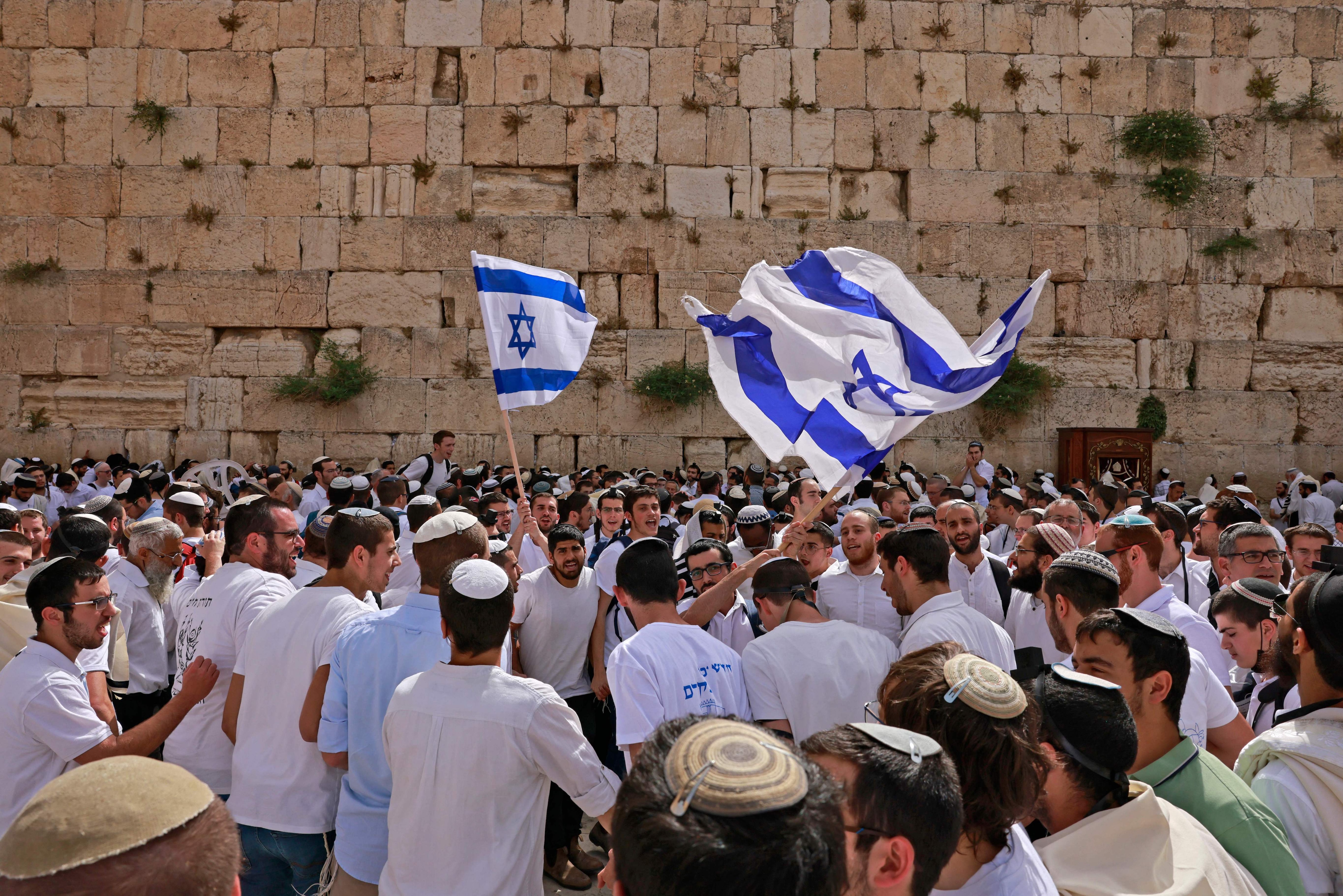 Jewish men wave Israeli flags as they gather at the Western Wall in the old city of Jerusalem on 10 May as Israel marks "Jerusalem Day".
