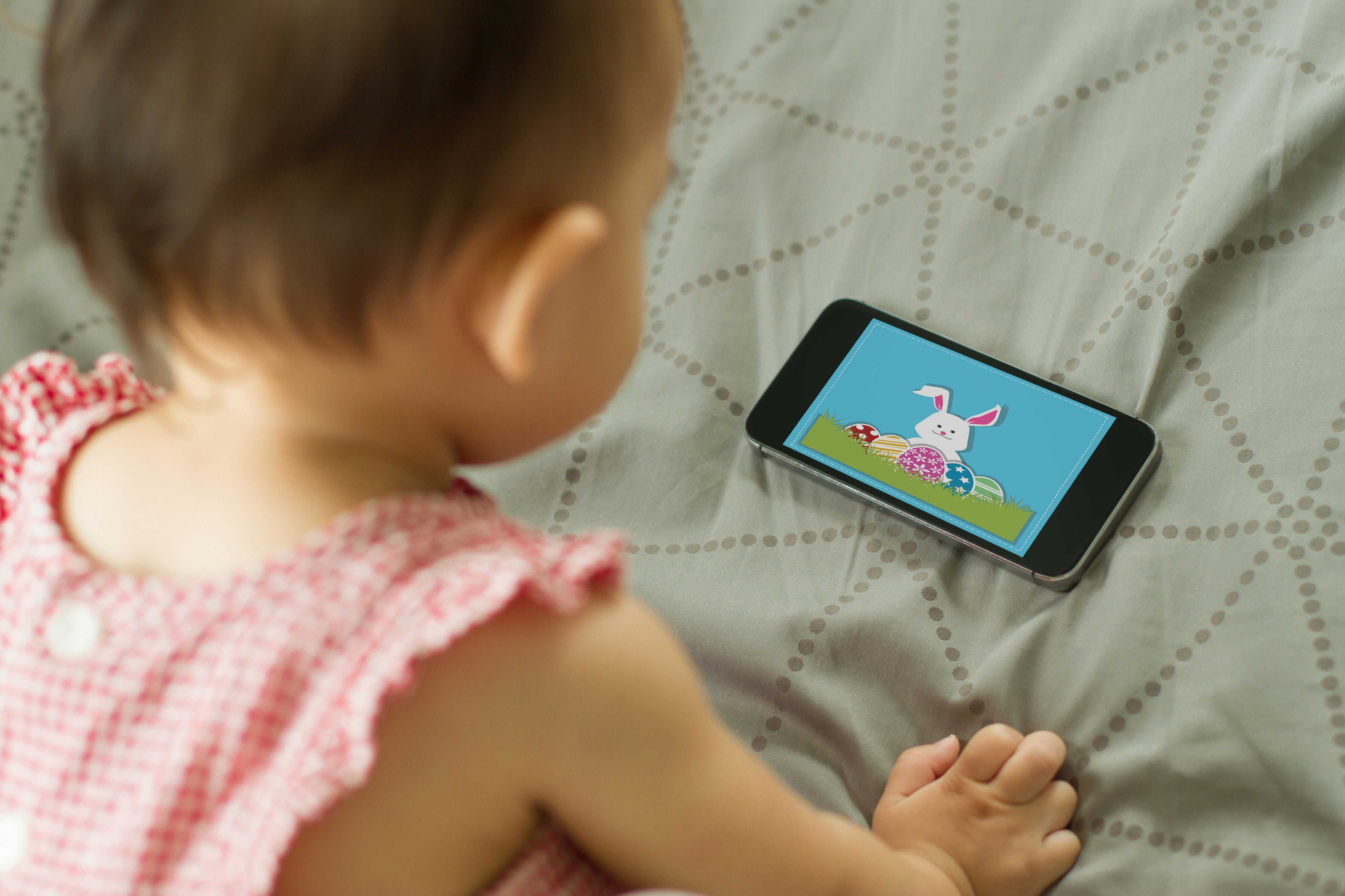 Baby looking at a colourful picture on a mobile phone screen.
