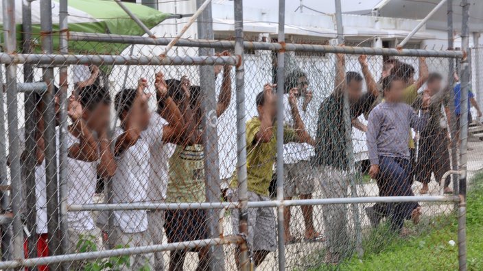 A file photo of asylum seekers standing behind a fence in the Oscar compound at the Manus Island detention centre.
