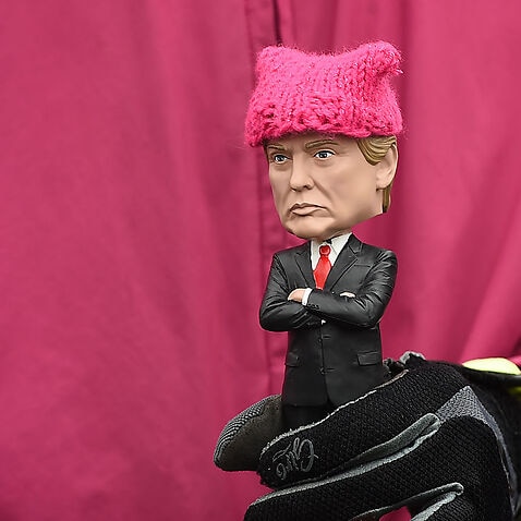 A protester, holding a Donald Trump doll wearing a pink cap, marches in Washington, DC, during the Womens March on January 21, 2017. 