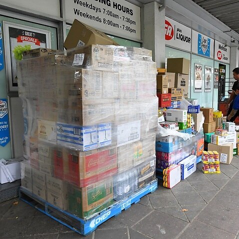 Employees of an IGA supermarket are seen unpacking stock outside their store in North Melbourne, 18 March 2020.  
