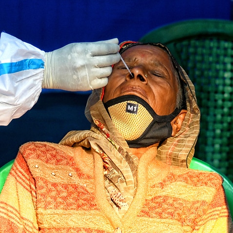A health worker wearing personal protective equipment (PPE) collects a nasal swab sample from a pilgrim for a Covid-19 rapid antigen test during the festival.