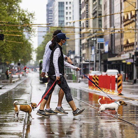 People are seen crossing Flinders Street in Melbourne.