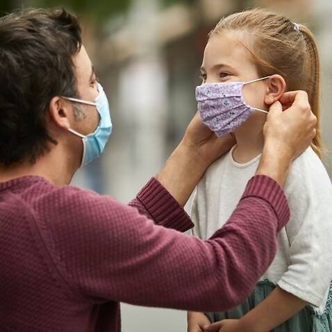 Father helps daughter with mask -  Getty Images - Morsa 