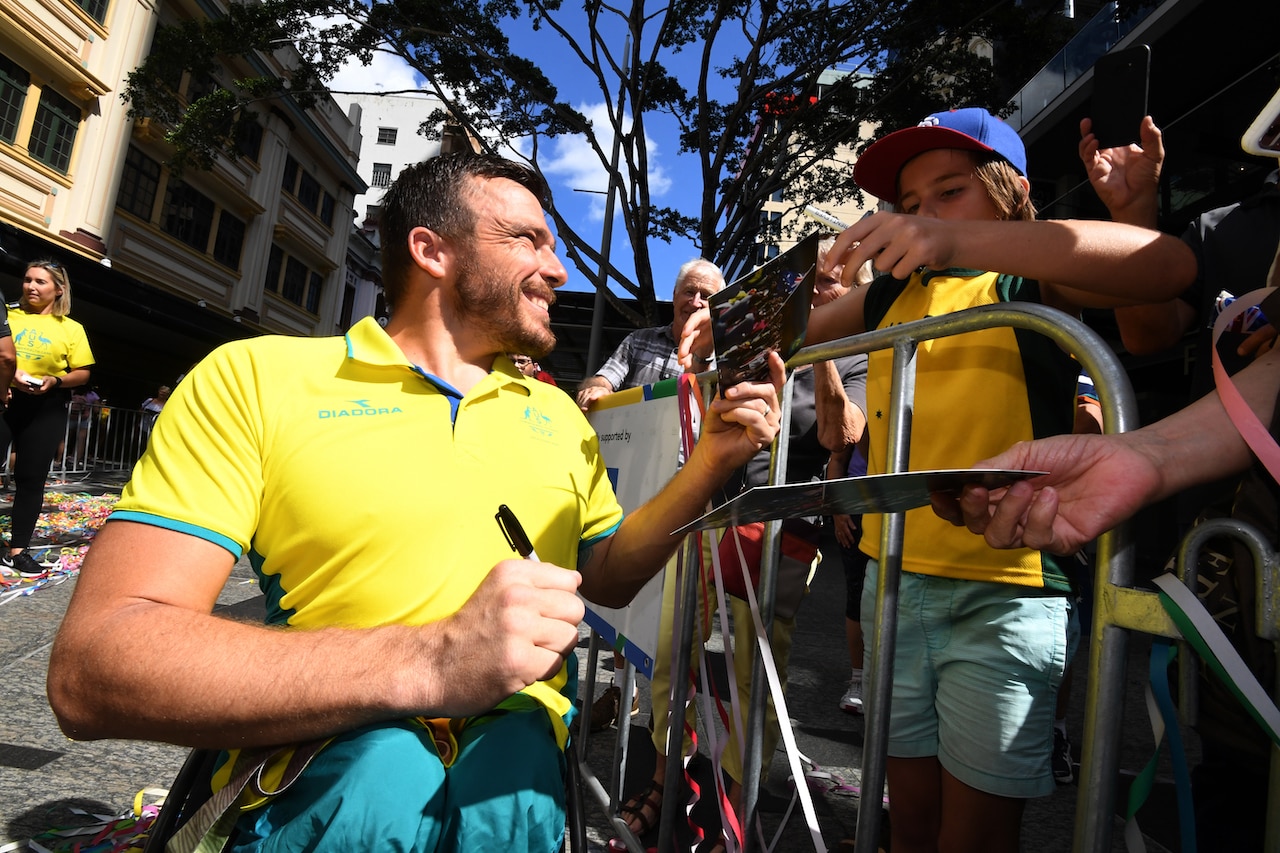 Commonwealth Games wheelchair race gold medalist Kurt Fearnley signs autographs during a street parade in 2018
