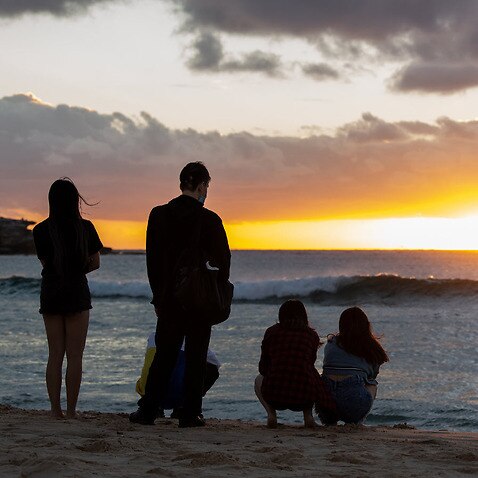 Revellers watch the sunrise on New Year’s Day at Bondi Beach in Sydney, Saturday, January 1, 2022.