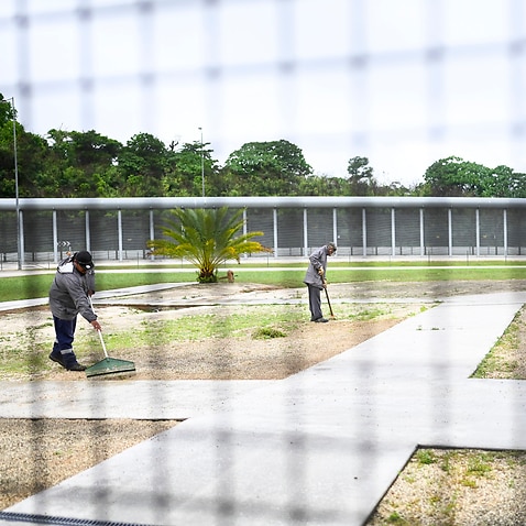 Staff work near the perimeter fence during a tour of the North West Point Detention Centre on Christmas Island