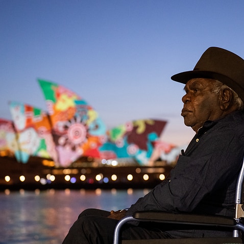 Artist and Pitjantjatjara man Yadjidta David Miller looks on as his artwork is projected onto the sails of the Sydney Opera House at dawn during Australia Day 2022 celebrations, in Sydney, Wednesday, January 26, 2022 (AAP Image/Bianca De Marchi) NO ARCHIV