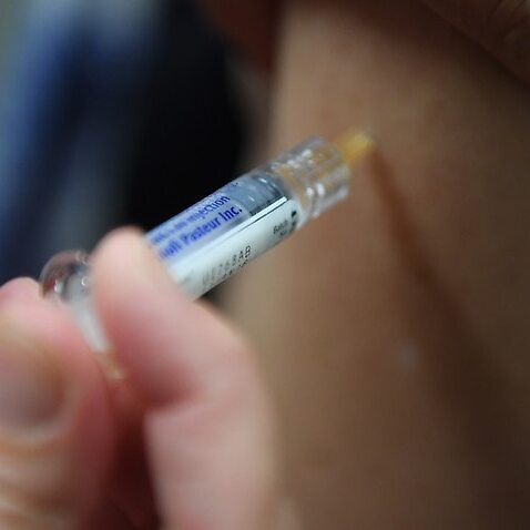 Image of a person being injected by a syringe on an arm.