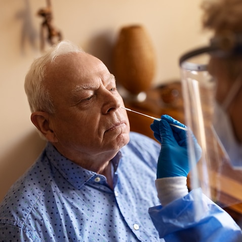 Healthcare worker taking sample for covid test of a senior man at home.