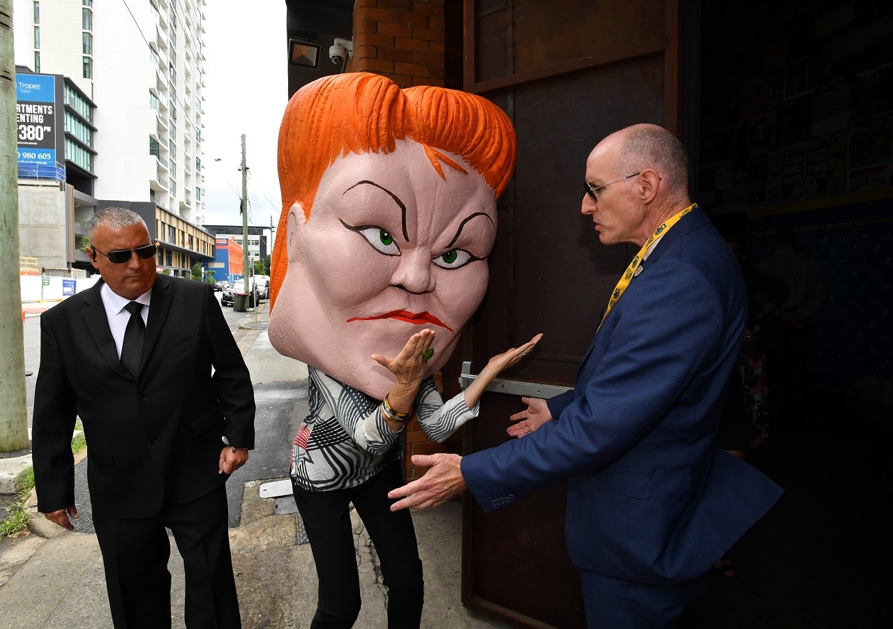 A protestor wearing a mask depicting Pauline Hanson.