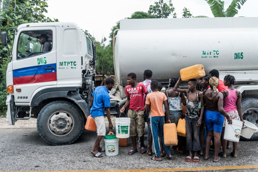 People gather near bins of water after the earthquake in Camp-Perrin, Haiti on 16 August, 2021. 