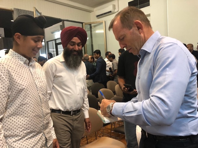 Tony Abbott signing an autograph for a young admirer from the Indian community