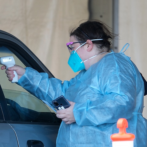 Health workers perform temperature checks at a drive-through COVID-19 Vaccination Centre in the suburb of Campbellfield, Melbourne, Monday, August 23, 2021. Victoria has recorded 71 new locally-acquired coronavirus cases, of which 49 are linked to known o