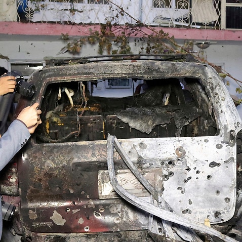 Afghan journalists take photos of a destroyed vehicle after a US drone strike in Kabul, Afghanistan, Sunday, August 29, 2021