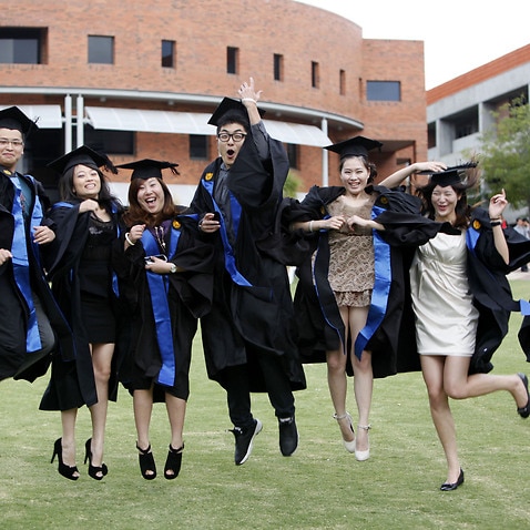 Chinese students studying abroad dressed in academic gowns pose during a graduation photo shoot at Curtin University in Bentley, Perth, Western Australia, Australia, 11 February 2012