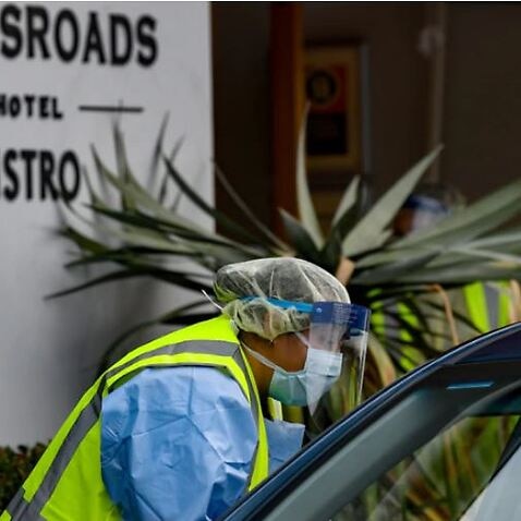 Workers administering COVID-19 tests to people in their cars at the Crossroads Hotel testing centre in Sydney,