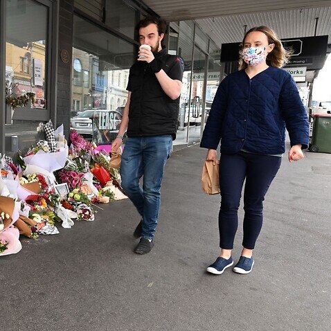 People walk past a floral tribute to a delicatessen owner who died from Covid-19 in Melbourne last year. (file)