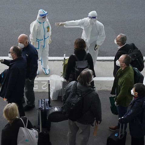 A worker directs members of the WHO team upon their arrival in Wuhan, January 14, 2021