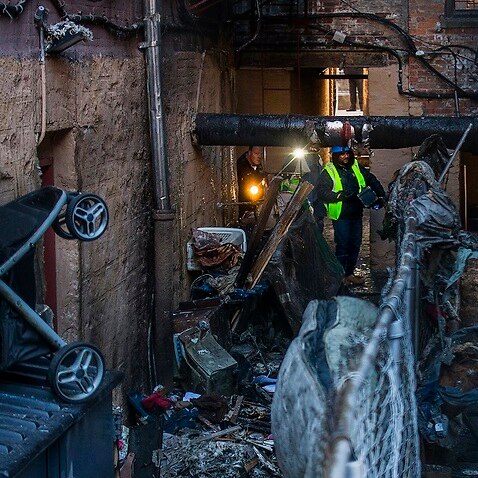 Police and workers check a building where twelve people died in a glow in a Bronx precinct of New York. 