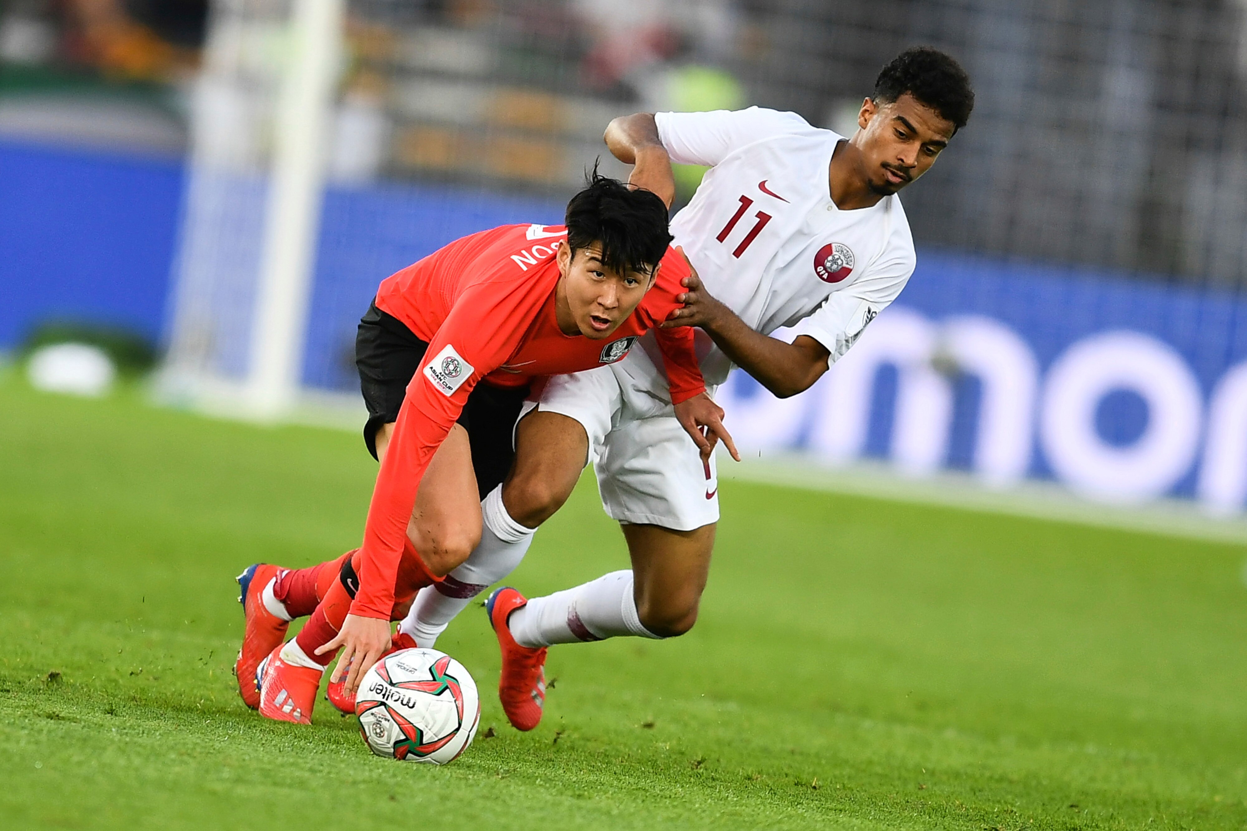 Son Heung-min, left, of South Korea national football team passes the ball against Akram Afif of Qatar 