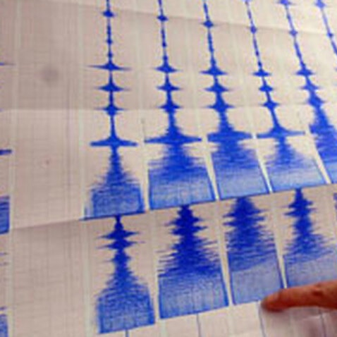 A seismologist points to a graph charting seismic activity