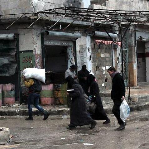 People carrying their belongings through the rebel-held al-Mashhad neighbourhood in Aleppo, Syria