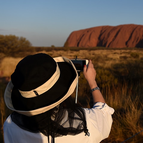 Tourists take photo at Uluru - AAP