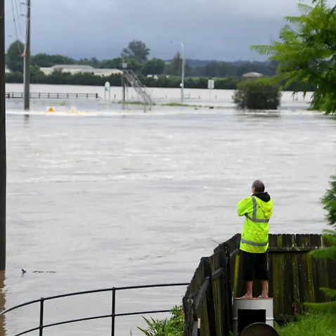 Residents watch over their fence as floodwater rises from the Hawkesbury river at Windsor, north west of Sydney, 3 March, 2022.
