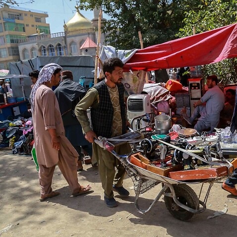 Afgan bir adam yiyecek almak için ev eşyalarını satıyor