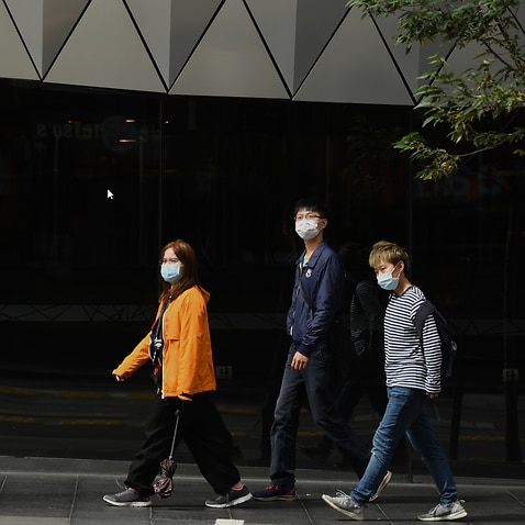 Pedestrians wear face masks in Sydney.