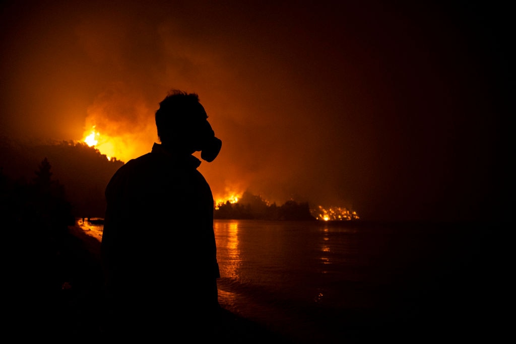 A man with a protective masks during a wildfirnear the village of Limni, on the island of Evia, Greece, on 6 August, 2021. 