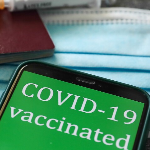 'COVID-19 vaccinated' sign displayed on a phone screen, passports, medical syringes and a face mask are seen in this illustration photo taken in Krakow, Poland on April 28, 2021