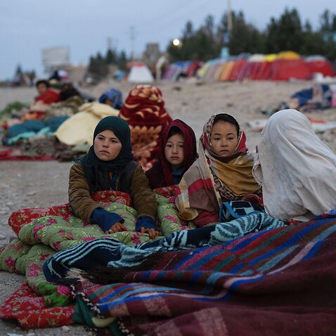 Afghan children are covered with a blanket as their families camp outside the Directorate of Disaster, in Herat, Afghanistan.