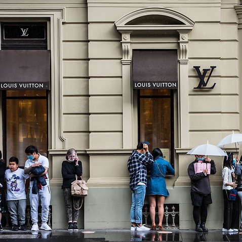 People seen lining up outside Louis Vuitton store in the rain on Collins Street in Melbourne.