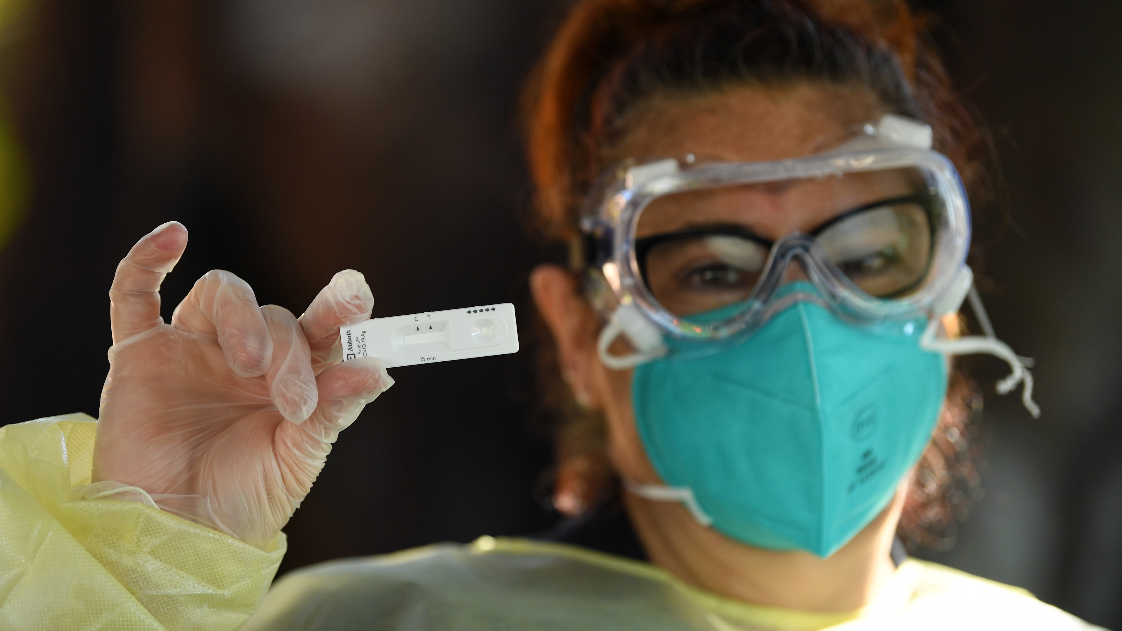 A healthcare worker holds up a COVID-19 rapid antigen test.