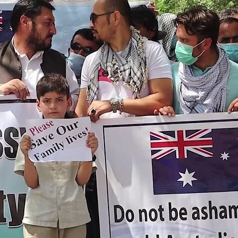 A child holds up a sign at a protest in Kabul by former Australian embassy staff, Sunday 18 July.