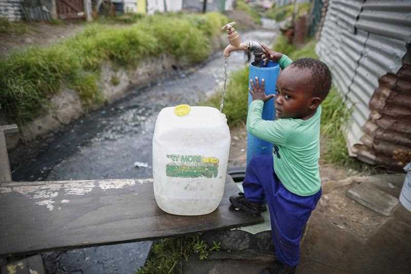 A resident of Masiphumelele informal settlement collects drinking water from a communal municipal tap in Cape Town, South Africa, 30 January 2018.