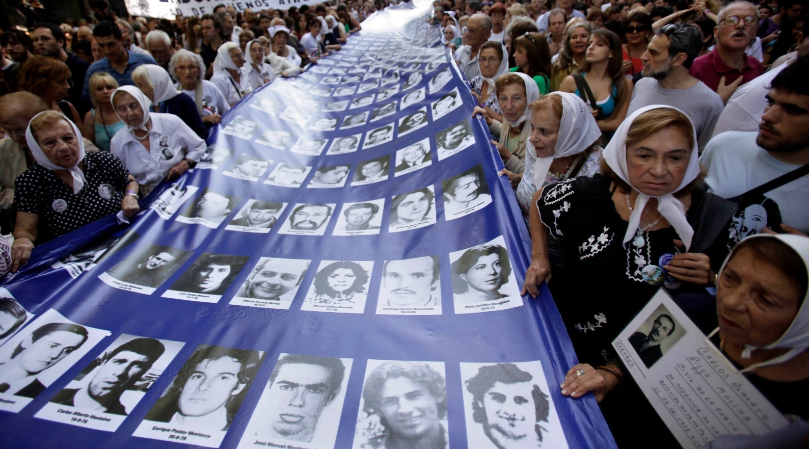 Members the Argentinian Grandmothers of the Plaza de Mayo carrying a banner with images of people missing during the dictatorship (AAP) Members the Argentinian Grandmothers of the Plaza de Mayo and Mothers of the Plaza de Mayo, carrying a banner with images of people missing