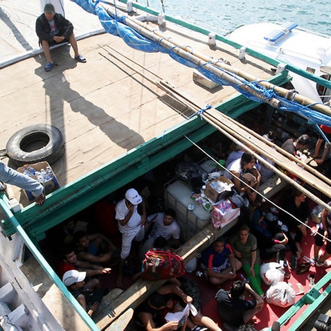 Asylum seekers who were caught in Indonesian waters while sailing to Australia sit on a boat at Benoa port in Bali, Indonesia. 