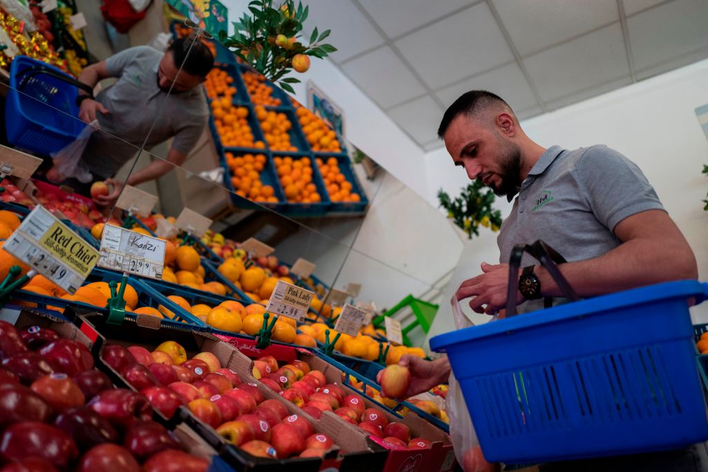 Abdulrahim Al Khattab, who came to Germany from Syria as a refugee, picks out fruit in grocery store in Berlin.