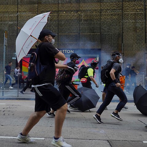Pro-democracy protesters and people run away from tear gas fired by riot police during a rally in Hong Kong.