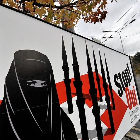 A woman walks behind a campaign posters